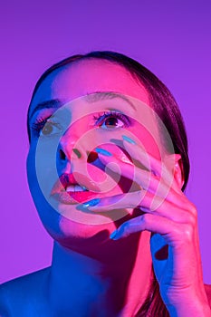 Fashion model woman with a bright make-up in colourful bright neon uv lights posing in studio