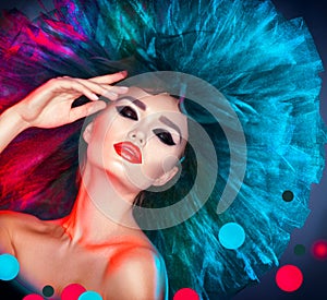 Fashion model woman in colorful bright lights posing. Beautiful girl with trendy makeup