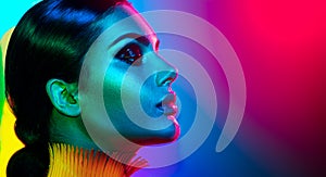 Fashion model woman in colorful bright lights posing. Portrait of girl with trendy makeup