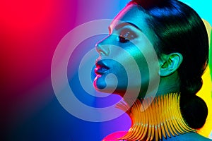 Fashion model woman in colorful bright lights posing. Portrait of girl with trendy makeup