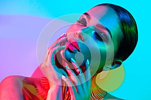 Fashion model woman in colorful bright lights posing in studio