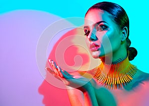 Fashion model woman in colorful bright lights posing in studio
