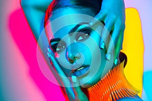 Fashion model woman in colorful bright lights with trendy makeup and manicure