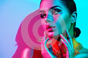 Fashion model woman in colorful bright lights with trendy makeup and manicure