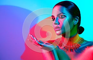 Fashion model woman in colorful bright lights with trendy makeup and manicure posing