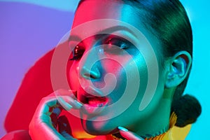 Fashion model woman in colorful bright lights with trendy makeup and manicure posing