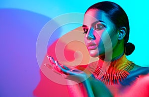 Fashion model woman in colorful bright lights with trendy makeup and manicure posing photo