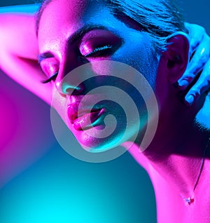 Fashion model woman in colorful bright neon lights posing. Portrait of beautiful girl in UV. Art design colorful makeup