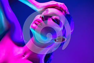 Fashion model woman in colorful bright neon lights posing in studio. Portrait of beautiful sexy dancing girl in UV