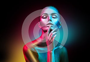 Fashion model woman in colorful bright sparkles and neon lights posing in studio, portrait of beautiful girl