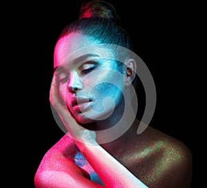 Fashion model woman in colorful bright sparkles and neon lights posing in studio, portrait of beautiful girl