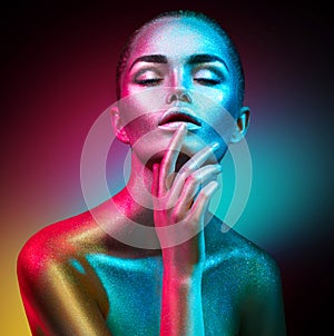 Fashion model woman in colorful bright sparkles and neon lights posing in studio, portrait of beautiful girl