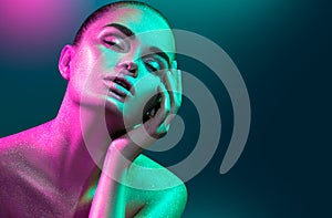 Fashion model woman in colorful bright sparkles and neon lights posing in studio, portrait of beautiful girl