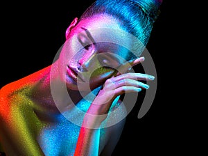 Fashion model woman in colorful bright sparkles and neon lights posing in studio, portrait of beautiful girl