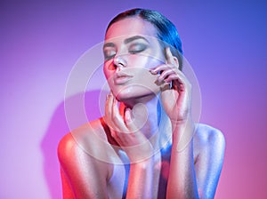 Fashion model woman in colourful bright sparkles and neon lights posing in studio, portrait of beautiful girl