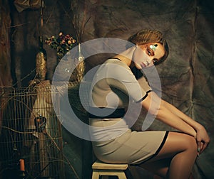 Fashion model woman with creative make up sitting on a stool in drama decoration