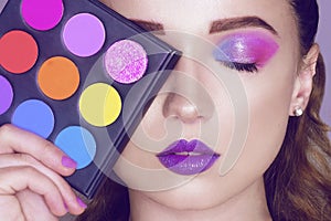 Fashion model woman creative pink and blue make up.  Beautiful Eyes Glitter . Purple bright lips, long cerly hair. Model holding