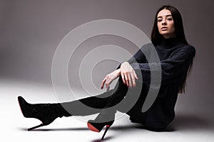 Fashion model woman in modern clothes sitting on the floor isolated on white background