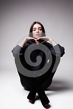 Fashion model woman in modern clothes sitting on the floor isolated on white background