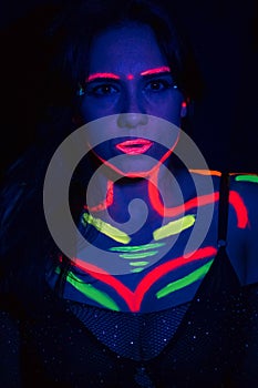 Fashion model woman in neon light, portrait of a beautiful model with fluorescent makeup, body art design in UV, painted