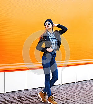 Fashion model woman wearing a rock black style posing over orange