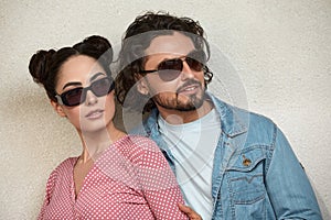 Fashion models couple wearing sunglasses. Sexy woman and handsome young man portrait over lite background. Attractive