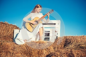 Fashion musician in white dress on sunny nature. Woman guitarist perform music concert. Albino girl hold acoustic guitar