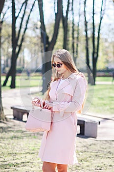 Fashion outdoor photo of beautiful young woman with blond hair in elegant clothes and sunglasses posing in sunny park