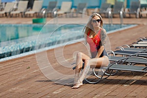 Fashion outdoor photo of gorgeous girl with blond hair in swimsuit relaxing near swimming pool