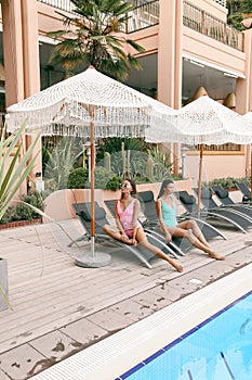 Women in elegant swimming suit relaxing near swimming pool