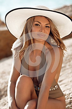 Fashion outdoor portrait of sensual bikini model in white hat. Carefree Woman Enjoying Beautiful Sunset on the Beach