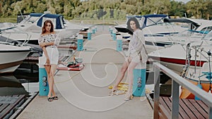 fashion outdoor video of two beautiful sexy girls in elegant dresses posing near yachts