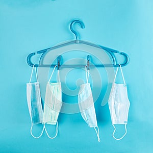 fashion outfit at pandemic time. face masks hanging on a rack over pastel blue background
