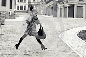 Fashion and people concept - happy young woman or teenage girl running and jumping high on city street