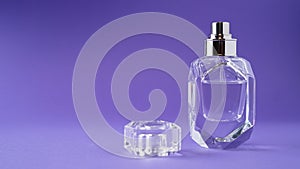 Fashion perfume in glass bottle on purple background. Diamond bottle shape. Transparent bottle. Crystal. Isolated