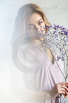 Fashion photo of a beautiful young woman in a beautiful dress with flowers, posing on a white background