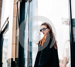 Fashion photo of beautiful young woman with sunglasses. Model looking at camera. City lifestyle. Female fashion.