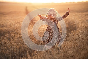 Fashion photo of a little girl in leopardprint dress, sunglasses and straw hat at the evening wheat field