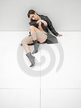 Fashion photo shoot in studio, on white background. Young beautiful woman emotionally and dramatically poses in black