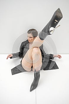 Fashion photo shoot in studio, on white background. Young beautiful woman emotionally and dramatically poses in black