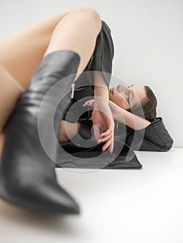 Fashion photo shoot in studio, on white background. Young beautiful woman emotionally and dramatically poses in black