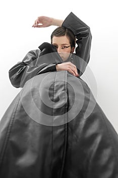 Fashion photo shoot in studio, on white background. Young beautiful woman emotionally and dramatically poses in black