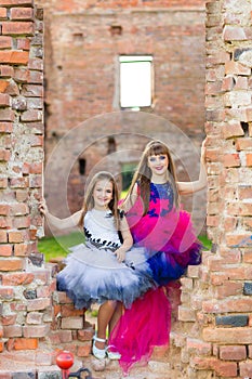 Fashion photo of two beautiful girls on a background of brick ru