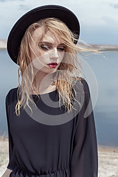 Fashion photo of young beautiful girl with wet hair in a black hat and a black cotton dress with beautiful bright makeup