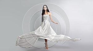 fashion photo of young girl in white dress flying tissue. Lightweight material.