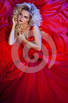 Fashion photo of young magnificent woman in red dress. Studio portrait