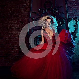 Fashion photo of young magnificent woman. Running towards camera. Seductive blonde in red dress with fluffy skirt