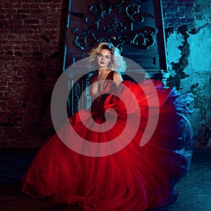 Fashion photo of young magnificent woman. Running towards camera. Seductive blonde in red dress with fluffy skirt