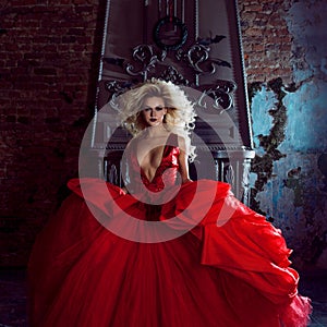 Fashion photo of young magnificent woman. Running towards camera. Seductive blonde in red dress with fluffy skirt