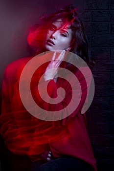 Fashion photo of young woman with makeup and hairstyle, wear red suit, red neon studio light.